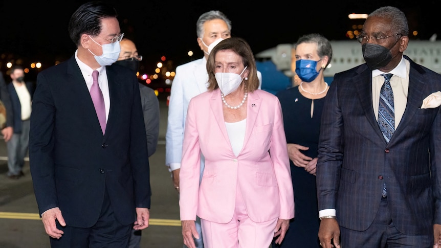 Nancy Pelosi walks on an airport tarmac with Taiwan's Foreign Minister.