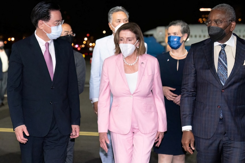 Nancy Pelosi walks on an airport tarmac with Taiwan's Foreign Minister.