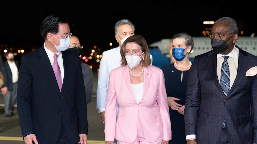 Nancy Pelosi walks on an airport tarmac with Taiwan's Foreign Minister.