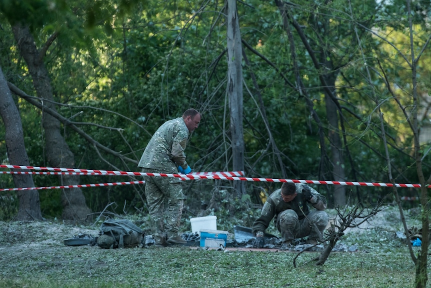 Police officers inspect the site of a Russian strike in Kyiv.
