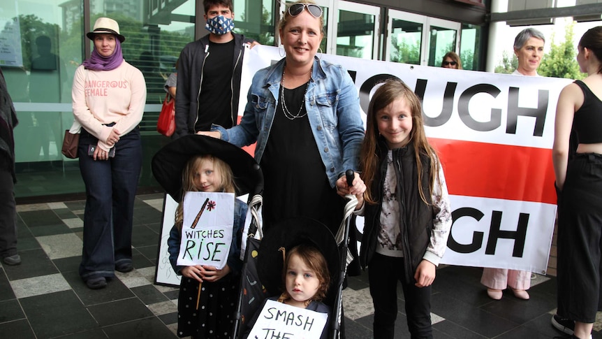 A woman stands with her daughters who are dressed up for the march for justice.