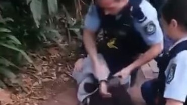 Two police officers restrain a teenager on the ground