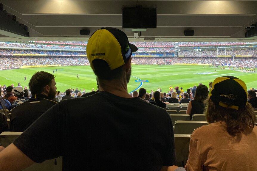 Back of tall man's head and ground in distance