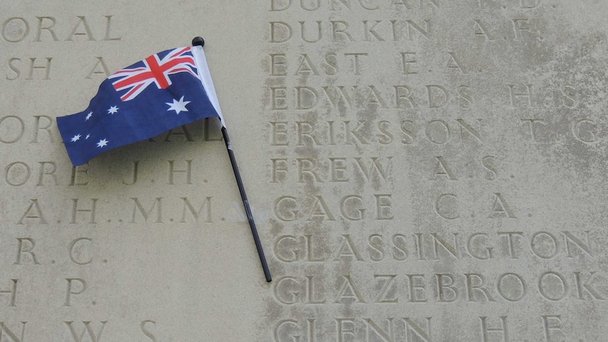 A cement wall with the names of WW1 soldiers engraved into it. An Australian flag sits next to the name of Charles Gage.