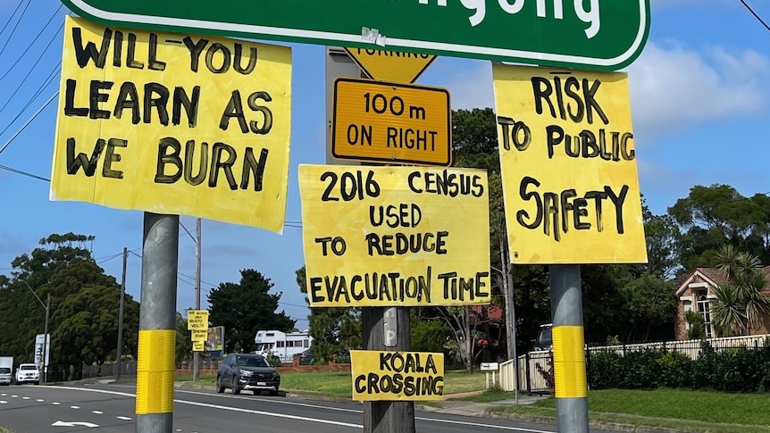 Yellow cardboard hand painted protest signs on the Appin traffic sign