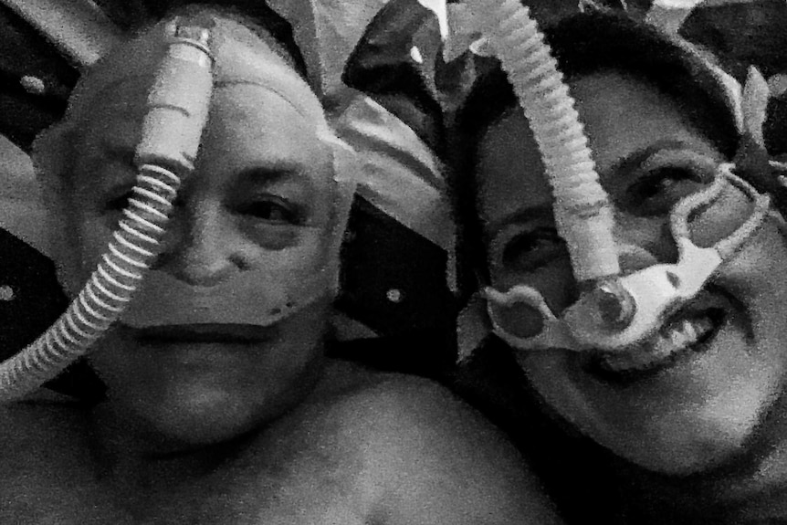 Grainy black and white image of man and woman's faces wearing CPAP masks
