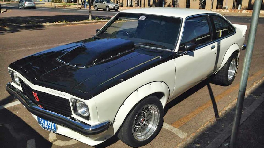 A black and white replica hatch back Holden Torana parked on a Darwin street.