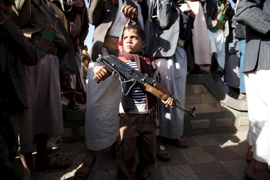 Boy stands with Houthis with Kalashnikov rifle