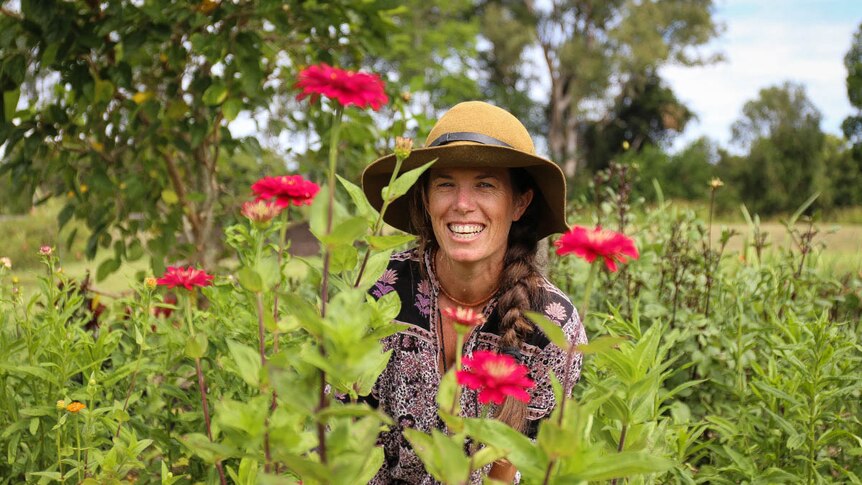 Hannah Lea Robertson smiling behind red flowers