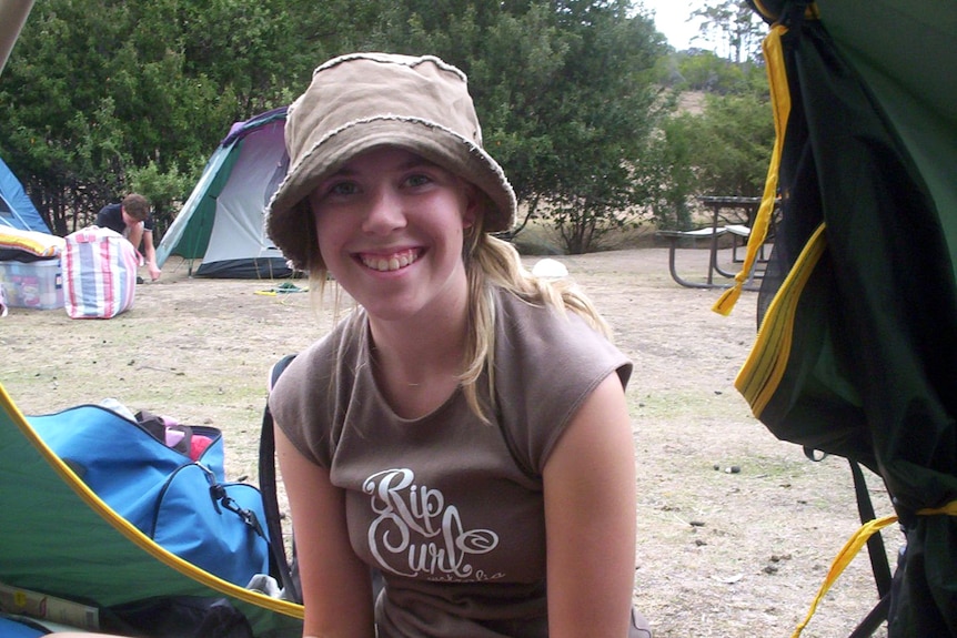 A 14 year old girl sits on the ground. 