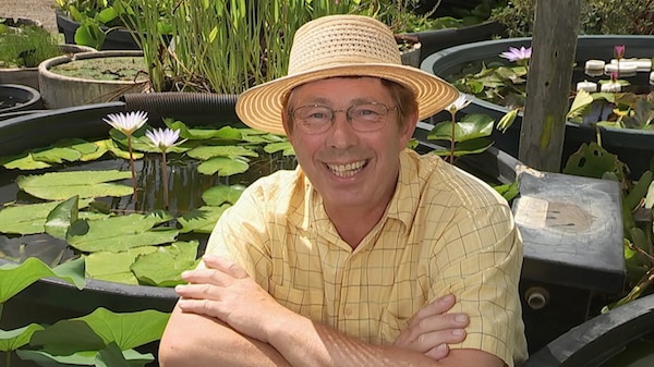 Jerry sitting in front of garden ponds filled with aquatic plants.