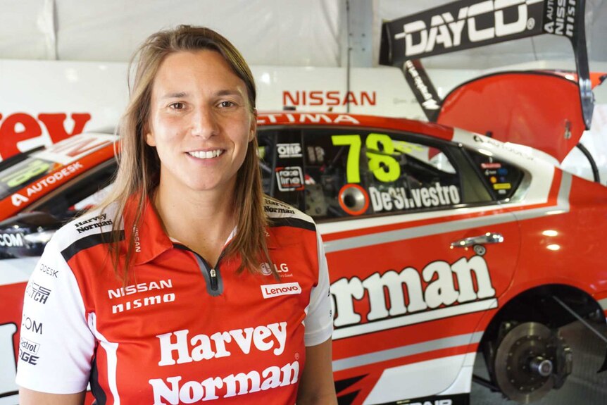 A woman standing in front of a racing car.