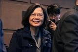 Ms Tsai smiles as she walks between security guards.