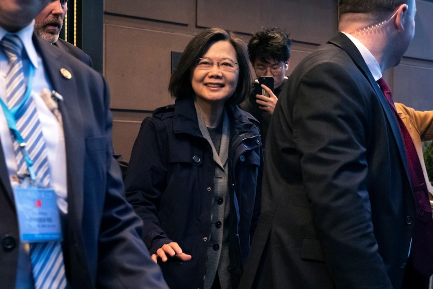 Ms Tsai smiles as she walks between security guards