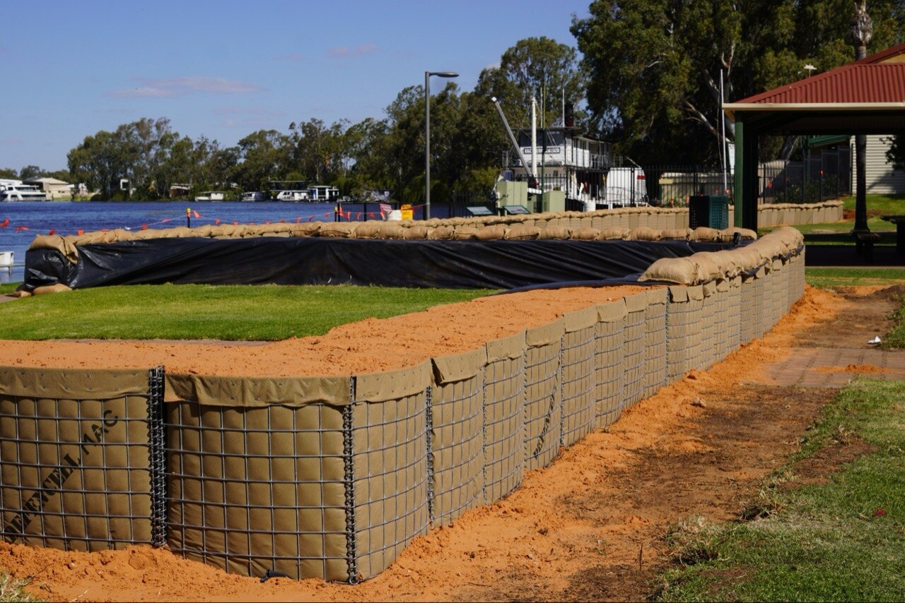 Large bags and metal poles filled with sand near a river