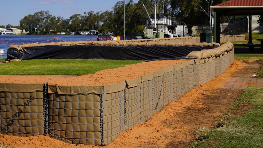 Large bags and metal poles filled with sand near a river