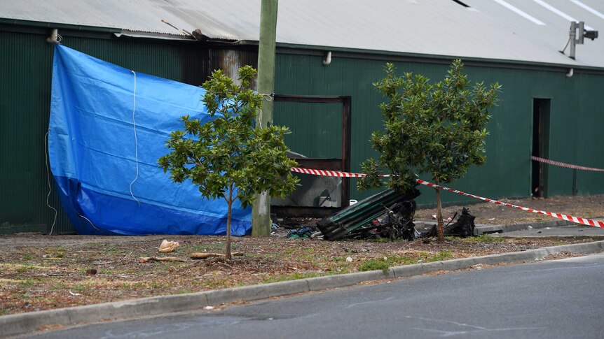 A blue tarp and police tape block the entry to a factory in Footscray after a fatal fire.