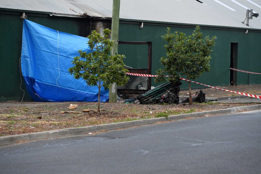 A blue tarp and police tape block the entry to a factory in Footscray after a fatal fire.