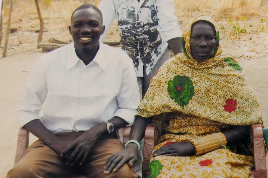 A young man in a white shirt next to an older woman with a headscarf on. 