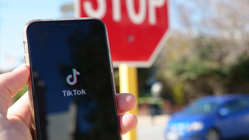 Tiktok app open on a phone with stop sign and car in background.