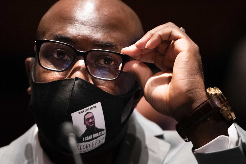 Philonise Floyd wears a protective face mask bearing an image of his brother George, and the words "I can't breathe".