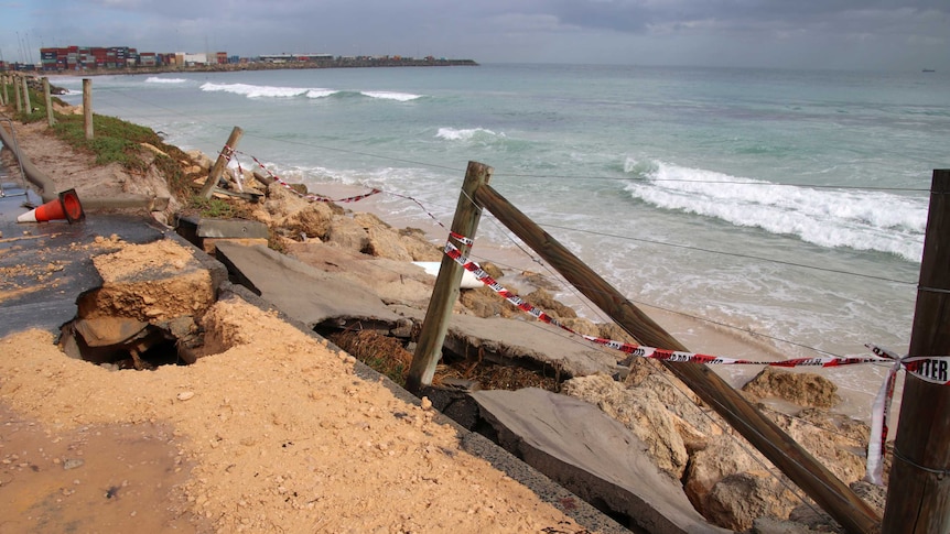 Eroded bitumen, concrete and fence with warning tape at Port Beach, Fremantle.