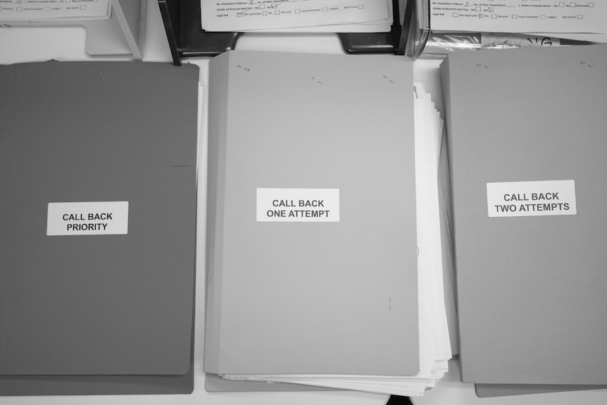 Three folders are laid out on an office table at a women's legal assistance organisation