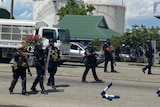Six armed police officers walk through the streets of Honiara.