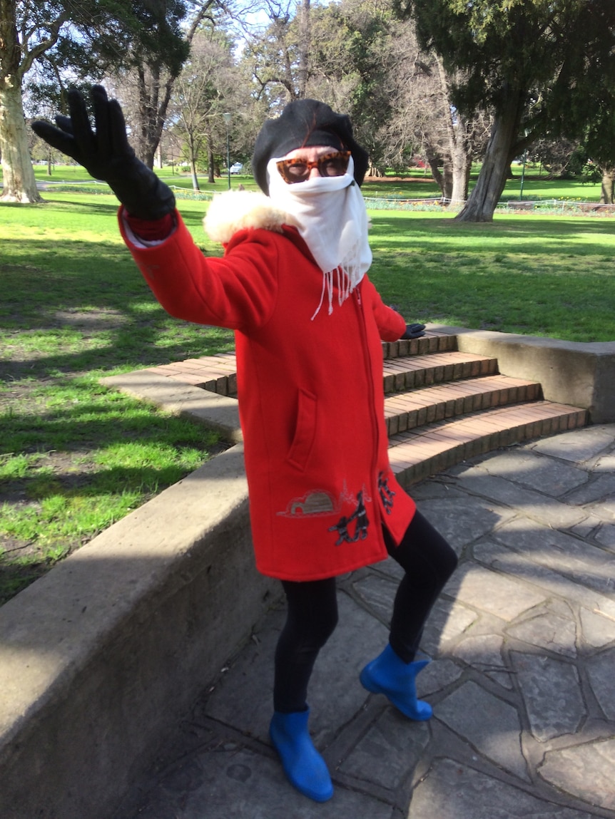 An older woman in a bright red coat and blue boots