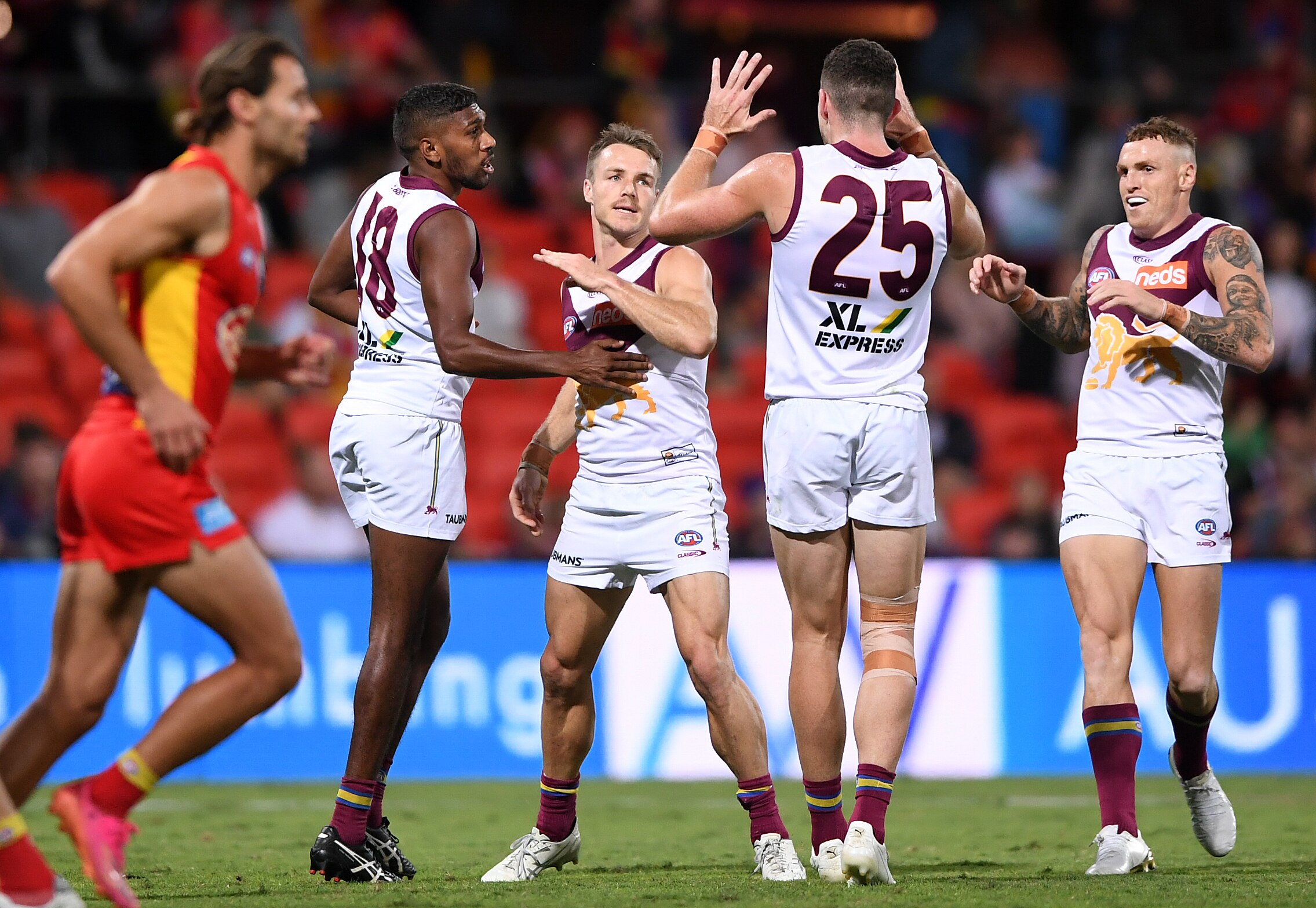 A Brisbane Lions forward accepts congratulations from teammates after a goal.