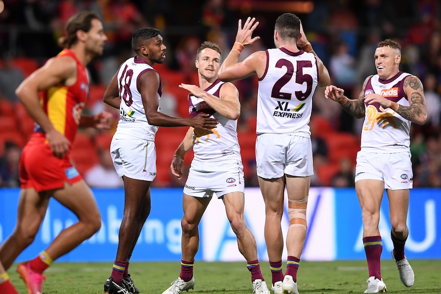 A Brisbane Lions forward accepts congratulations from teammates after a goal.