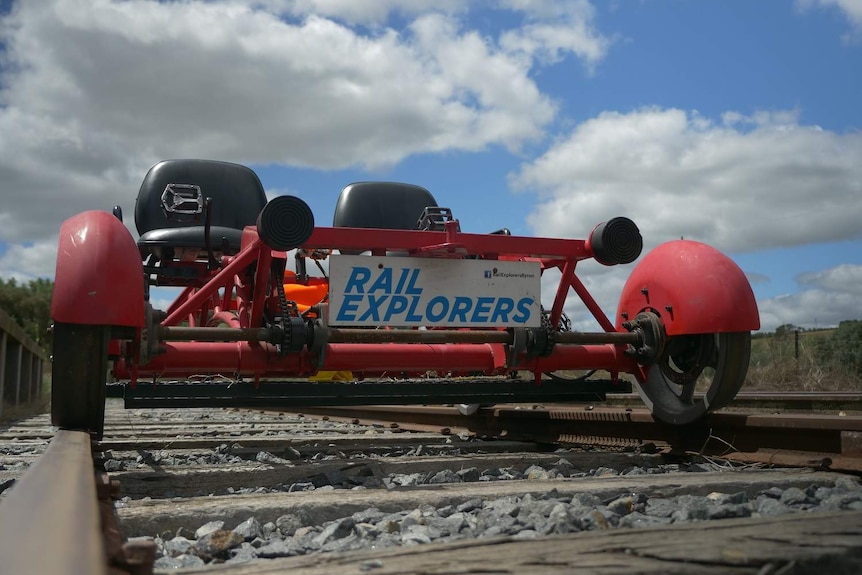 A red tandem bike specifically built to fit onto railway tracks.