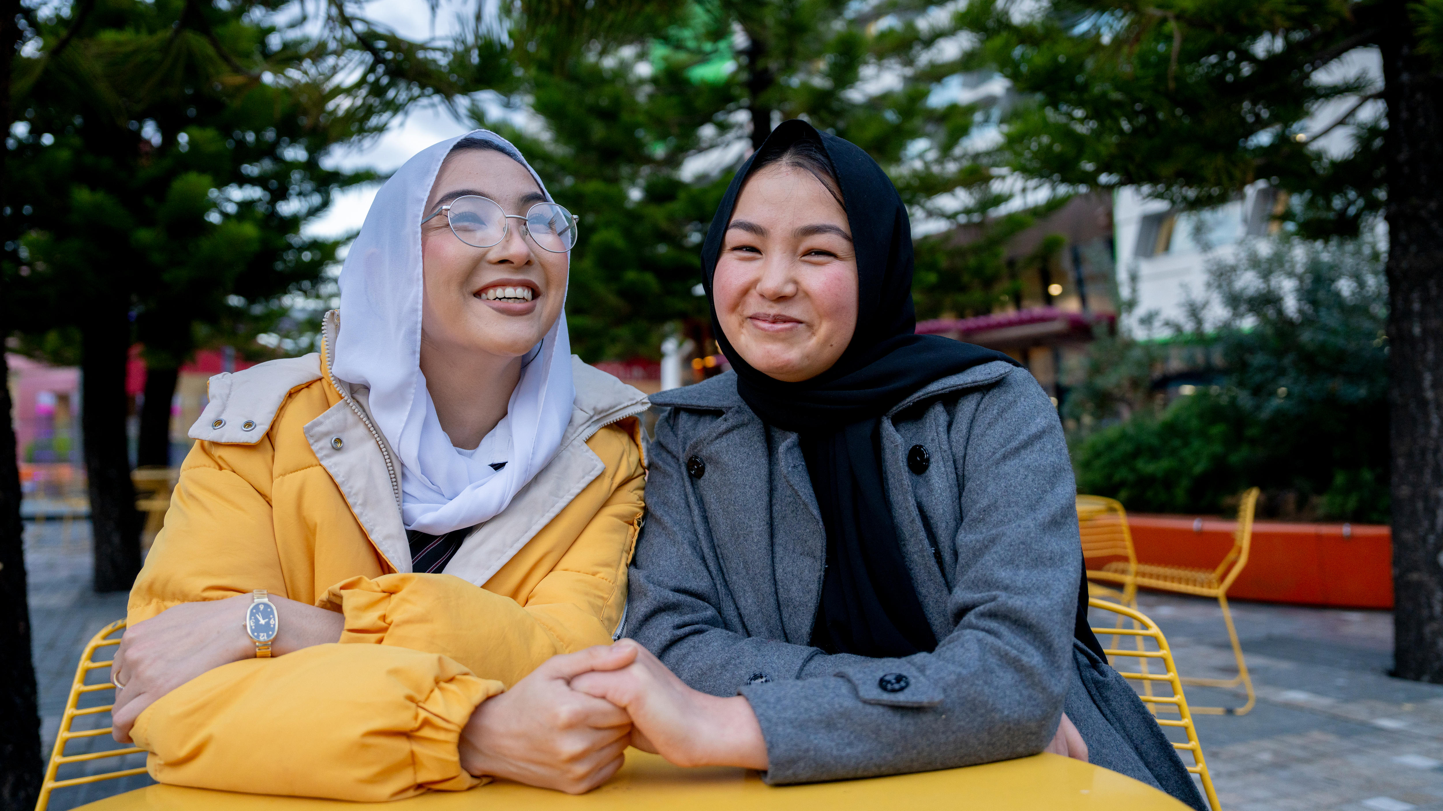 Adiba and Arya, two sisters, holding hands, smiling