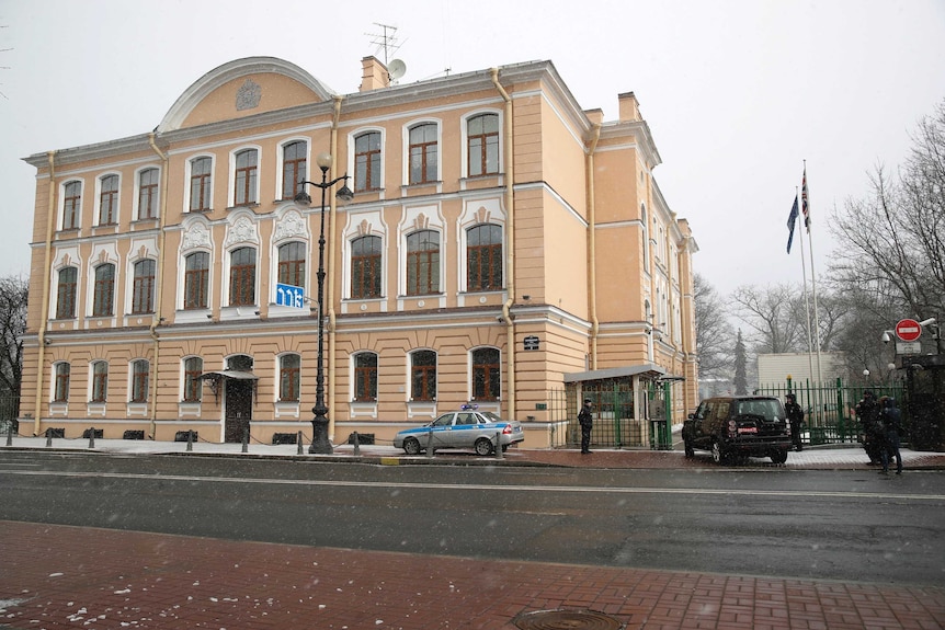 Wide shot of a cream-coloured building with guards in front of it.