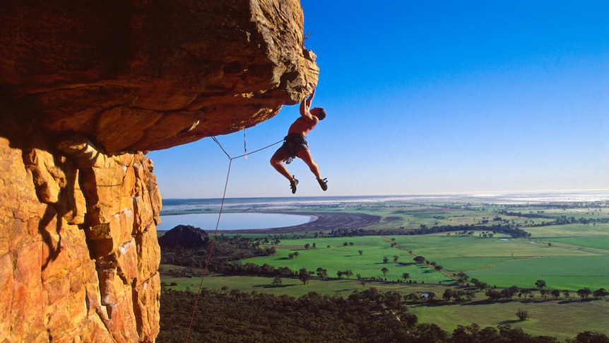 A rock climber swinging across the rook of Kachoong in the Northern Group at Mt Arapiles.