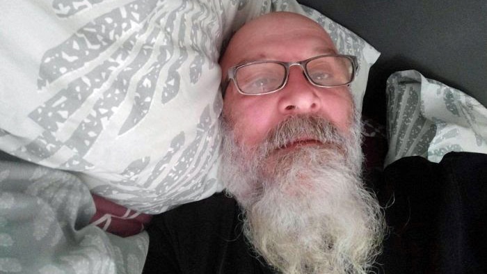 A man rests his head on a pillow.