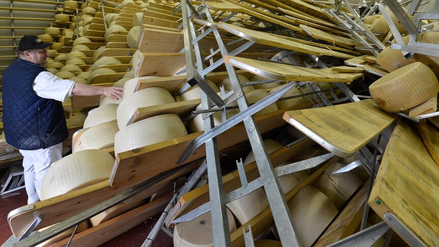 Oriano Caretti looks at the broken shelves housing blocks of cheese after the earthquake.