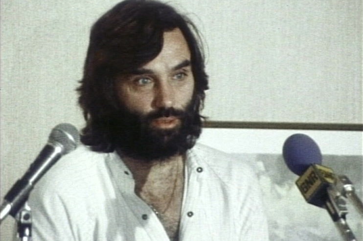 A mid shot of Northern Ireland superstar George Best speaking during a media conference in front of two microphones.