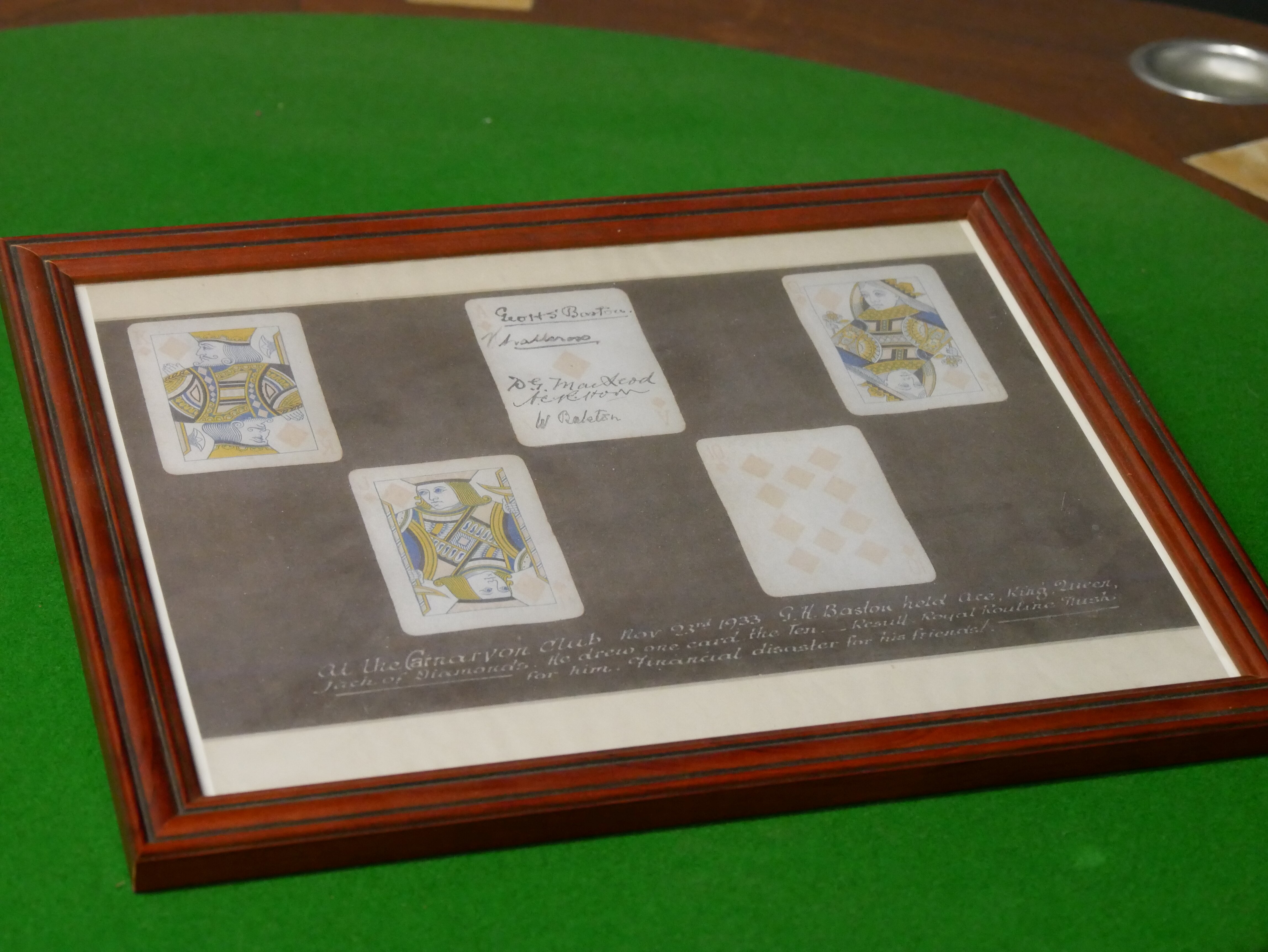 A 10, jack, queen, king and an ace of diamonds mounted in a picture frame. The ace has several signatures written on it.