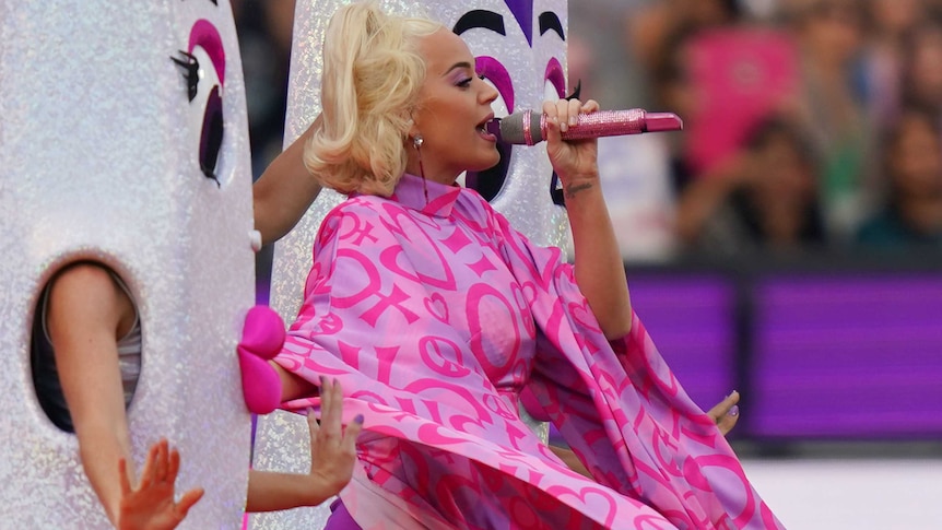 Katy Perry, surrounded by giant cricket bats with effeminate faces, sings on the MCG.