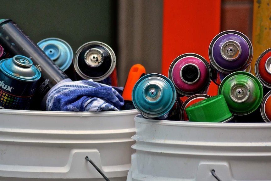 Colourful aerosol paint cans in bins.