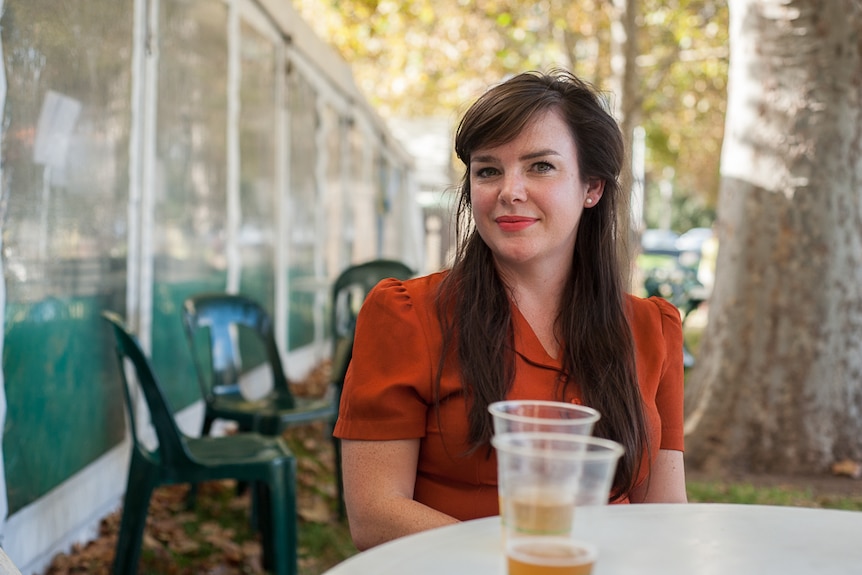 Margot McInnes wearing bright lipstick and drinking a beer at the Adelaide Writers' Festival