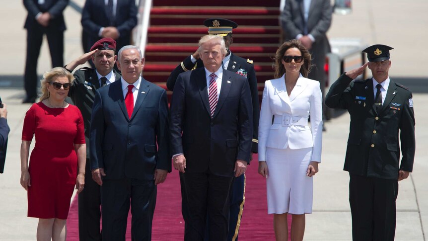 Donald and Melania Trump stand beside Benjamin and Sara Netanyahu. A red carpet, plane steps and saluting men are visible.