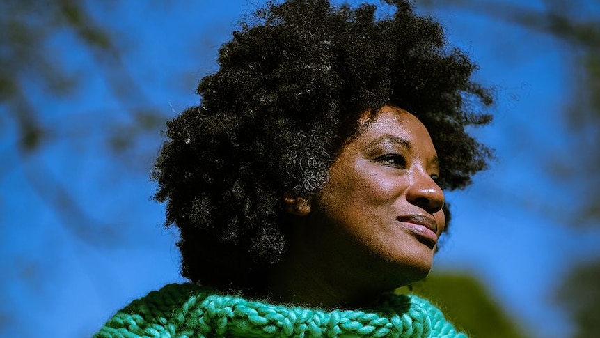 Black woman wearing a bright green turtle neck knitted jumper