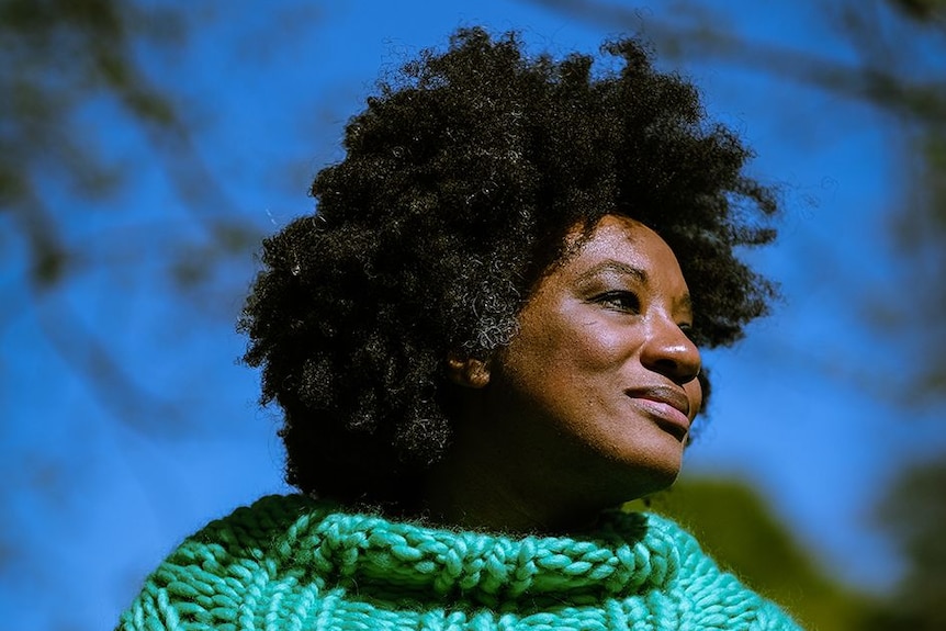 Black woman wearing a bright green turtle neck knitted jumper