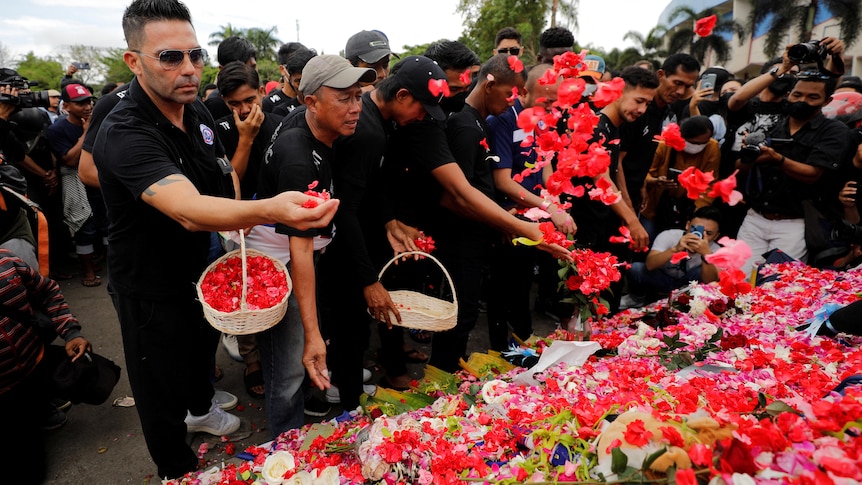 People put petals on a monument as they pay condolences to the victims of a stampede