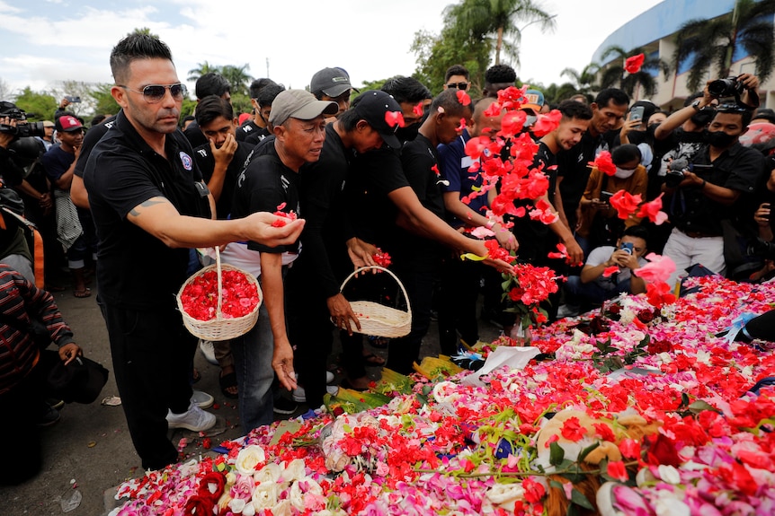 People put petals on a monument as they pay condolences to the victims of a stampede