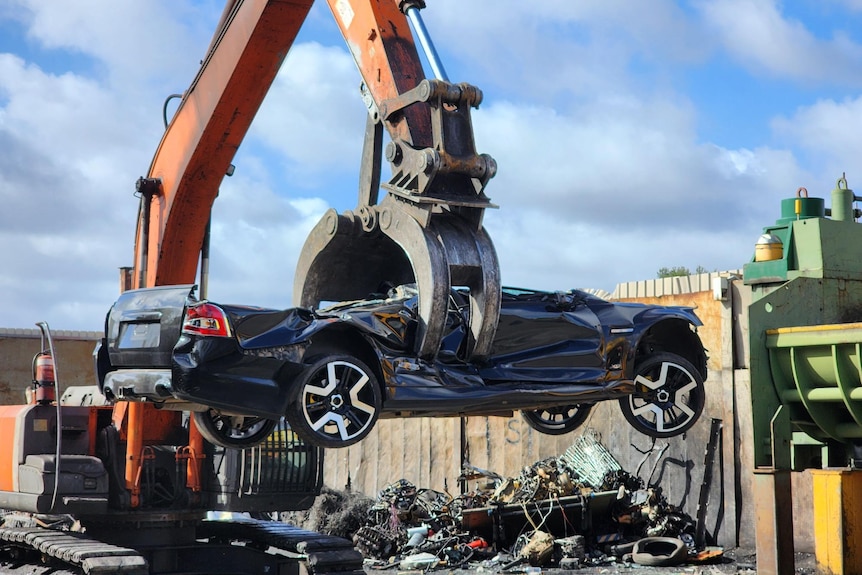 A Holden ute lifted into the air by a crane