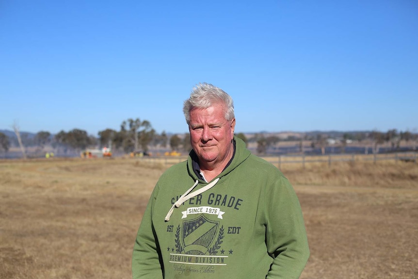 Kerry Bowman standing in a field with firefighters behind him.