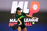 A player prepares to hit a ball with a paddle in front of a Major League Pickleball sign.